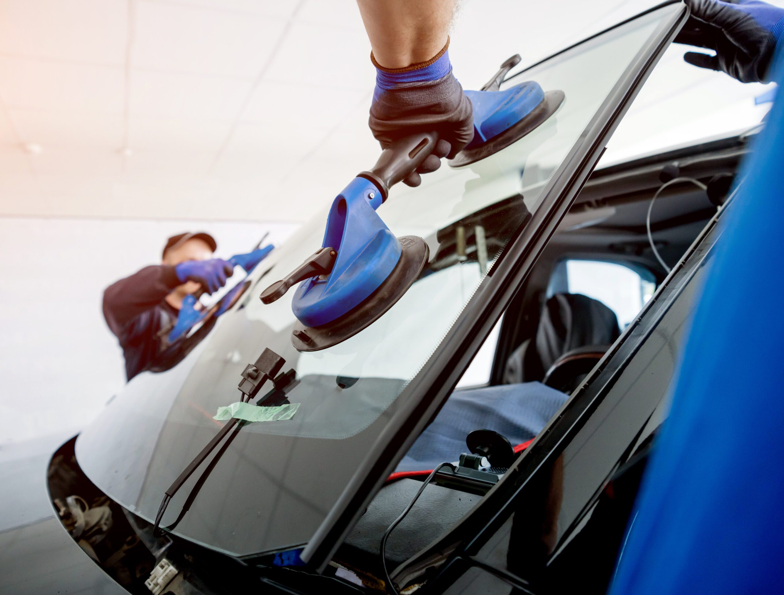 Windshield being replaced by two auto glass technicians