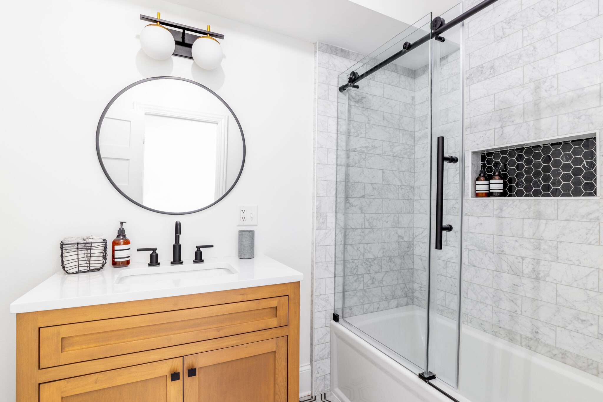Glass shower door with black hardware and wood vanity